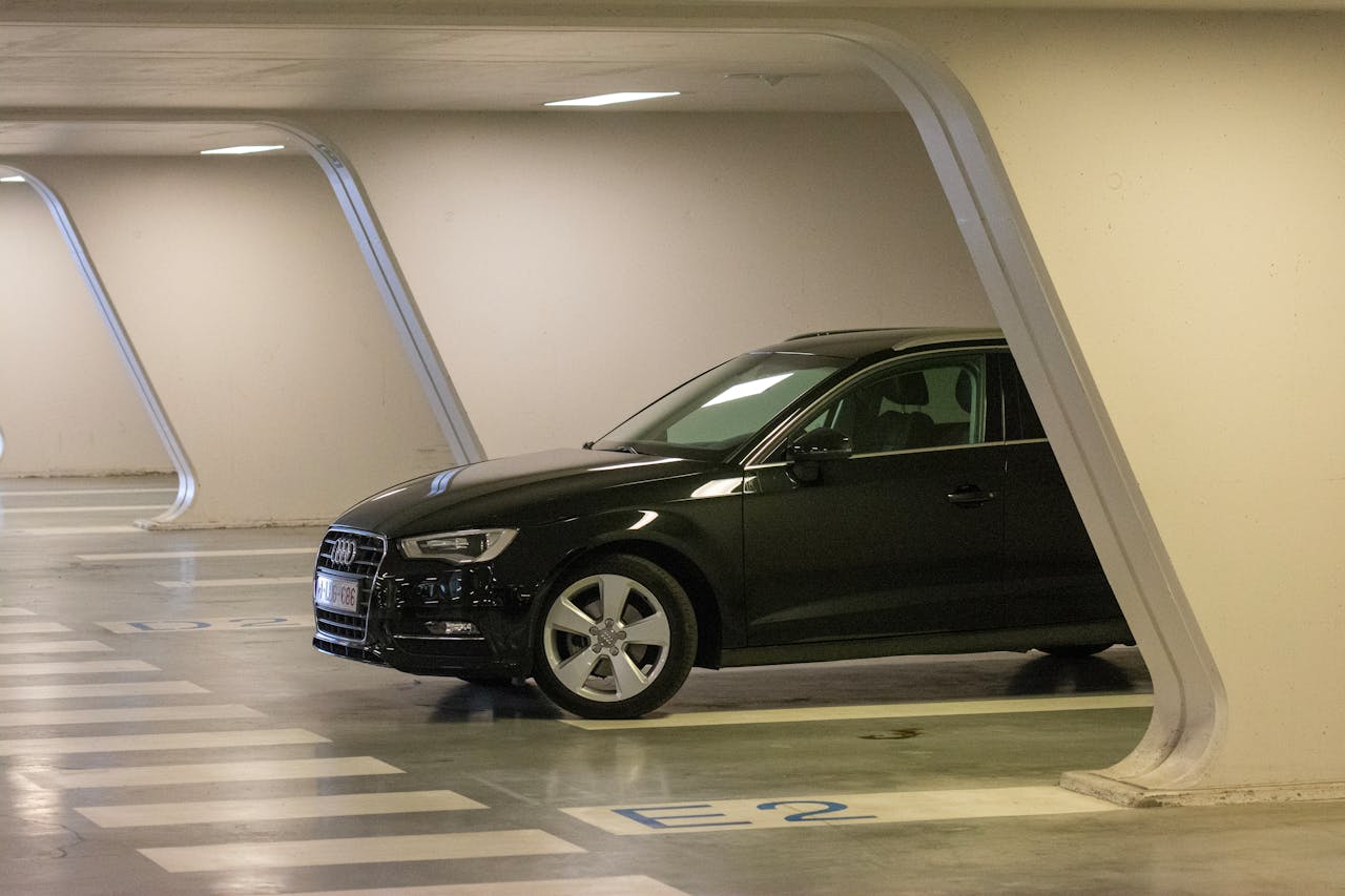 Black Audi A3 car parked in a modern underground garage, showcasing automotive design.